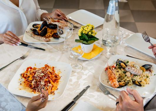 Table set with pasta and seafood risotto dishes.