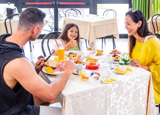 Happy family having breakfast in a bright restaurant.