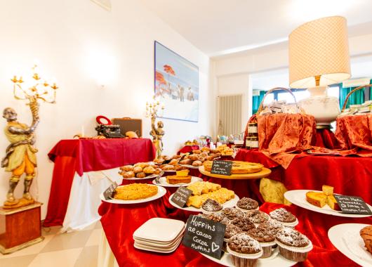 Dessert buffet with cakes and muffins on decorated tables.