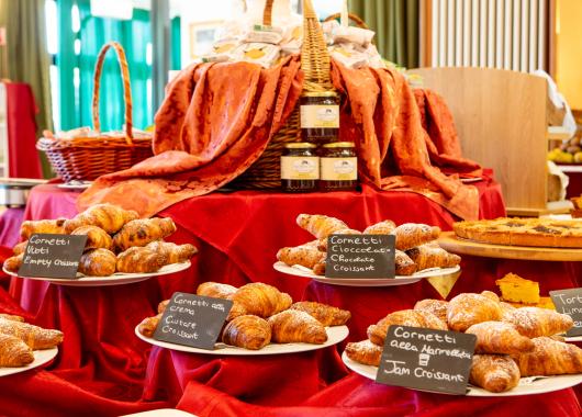 Buffet of assorted croissants with jams and cakes.