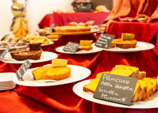 Variety of desserts on tables with red tablecloths.