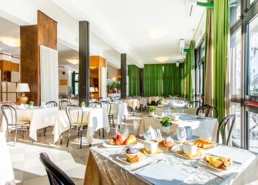 Bright dining room with tables set for breakfast.