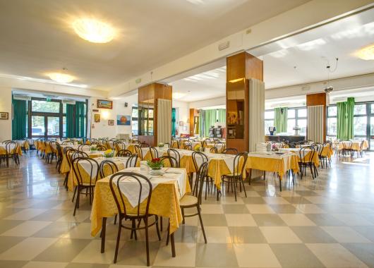 Spacious dining room with set tables and wooden chairs.