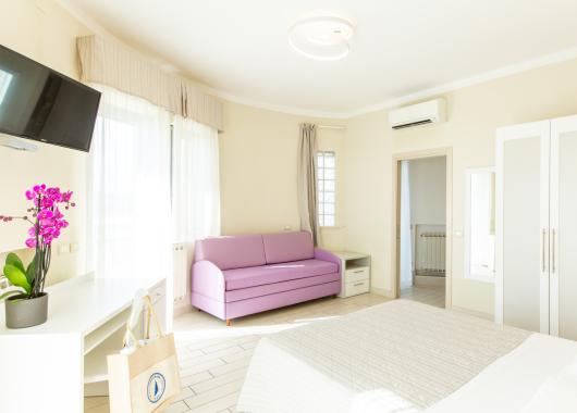 Bright room with purple sofa, TV, and air conditioning.