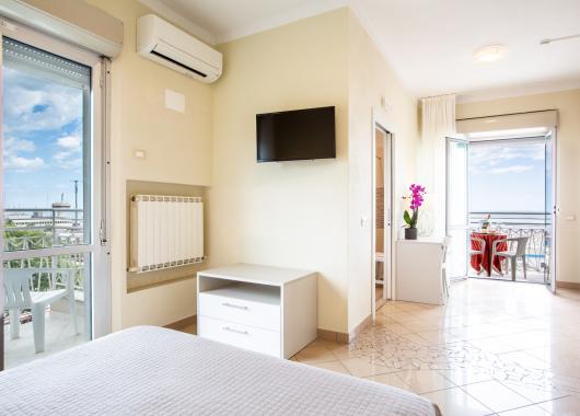 Bright room with sea view balcony, TV, and air conditioning.