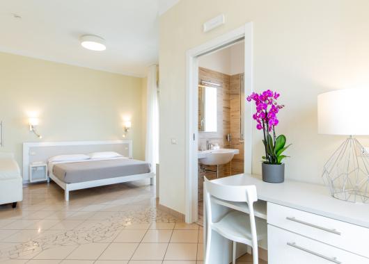 Bright room with bed, desk, and private bathroom.