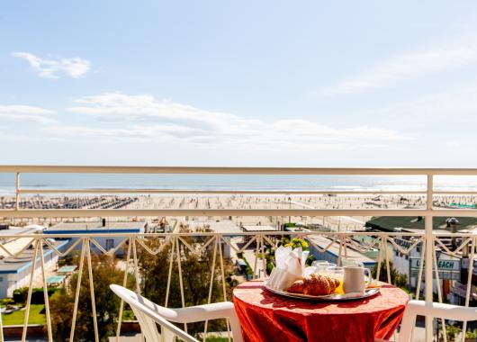 Breakfast on a terrace with a sunny beach and sea view.