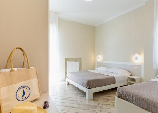 Bright room with two beds, modern decor, and a beach bag.