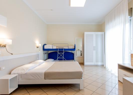 Bright room with a double bed and bunk beds.