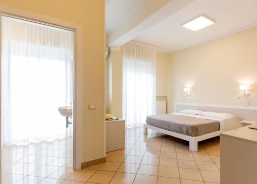 Modern room with double bed and bright bathroom.