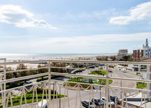Sea view from a balcony with white chairs.