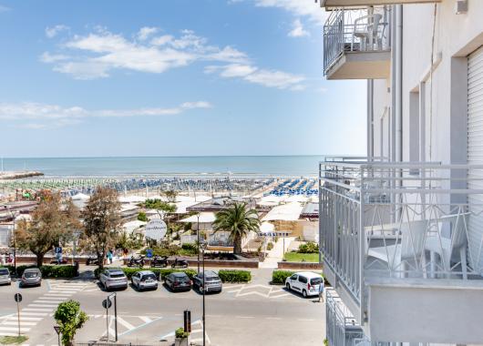 Sea view from a balcony with beach and umbrellas.