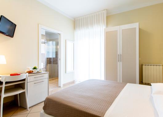Modern room with bed, wardrobe, desk, and bathroom.