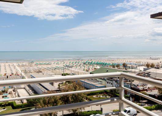 Sea view with beach and green umbrellas, clear sky.