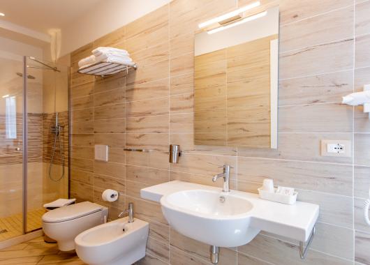 Modern bathroom with shower, sink, and bidet, wood-effect tiles.