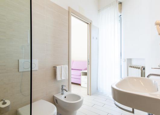 Modern bathroom with bidet and sink, view towards a room.
