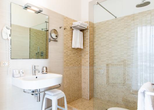 Modern bathroom with shower, mirror, and sink.