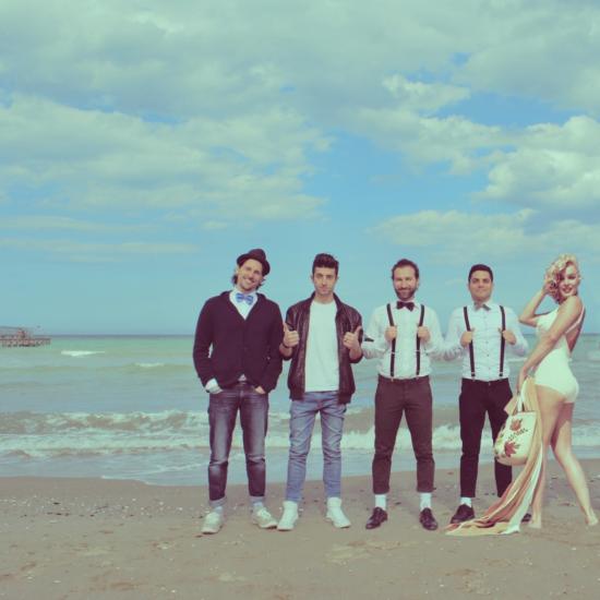 Gruppo di persone in posa sulla spiaggia con abbigliamento vintage.