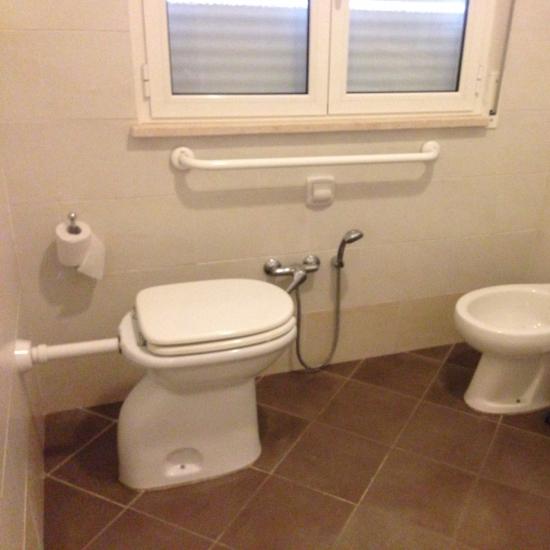 Bagno con WC, bidet e scaffale.