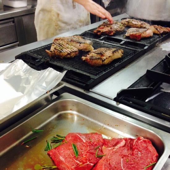 Carne cruda e grigliata con rosmarino in una cucina.