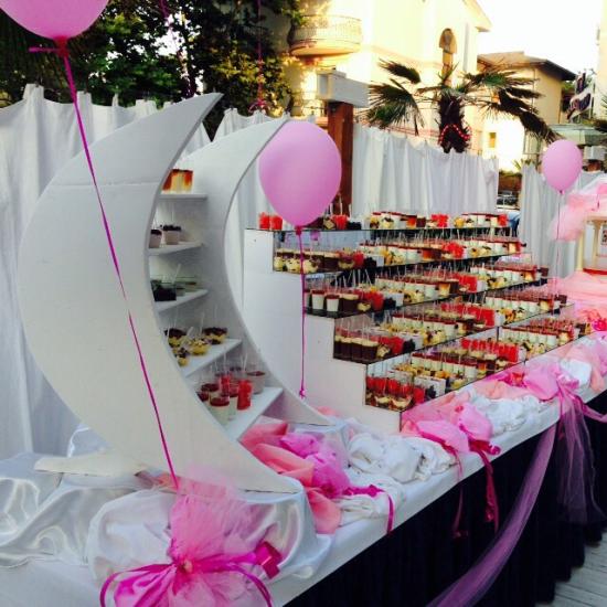 Buffet con dolci, decorazioni rosa e palloncini per una festa elegante.