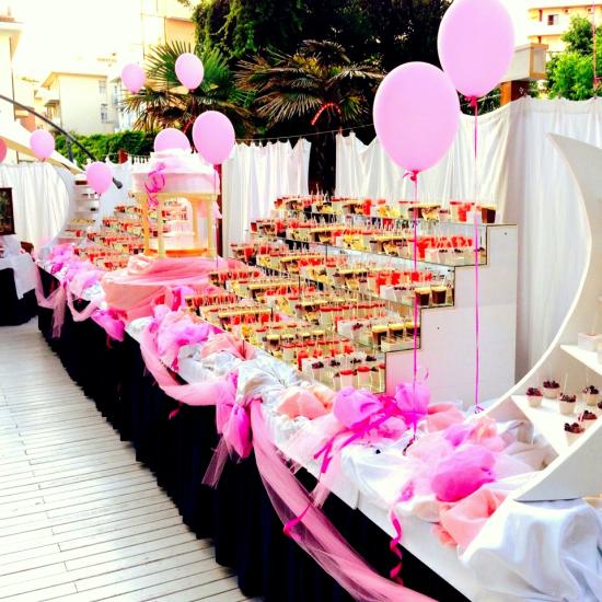 Buffet dolci decorato con palloncini rosa e tema lunare.