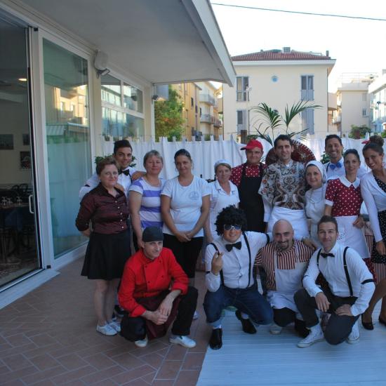 Gruppo di persone in abiti vintage all'aperto, sorridono per una foto.