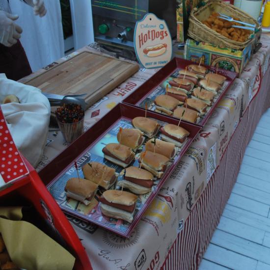 Buffet con hot dog e snack su tavolo decorato.