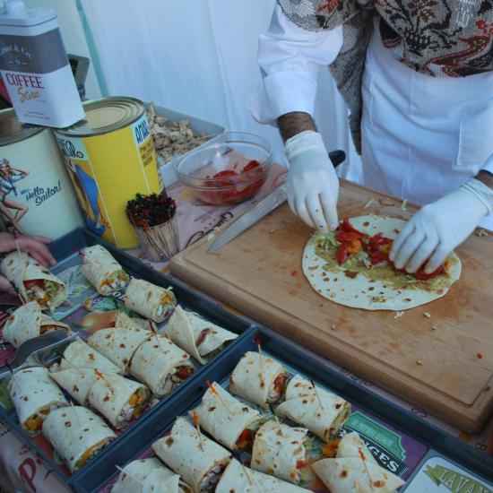 Preparazione di wrap con verdure e salse su tavolo da cucina.