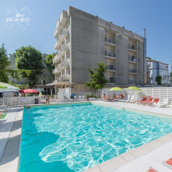 Piscina all'aperto con lettini e ombrelloni verdi.