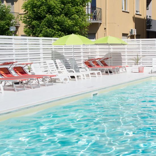 Piscina all'aperto con lettini e ombrelloni verdi.