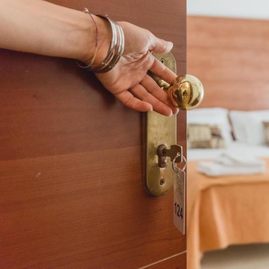 Mano apre porta di una camera d'albergo accogliente.