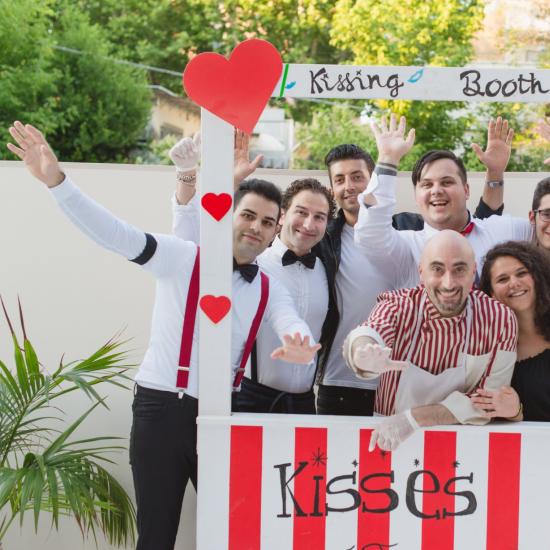 Gruppo di persone felici in un chiosco dei baci con cuori rossi.