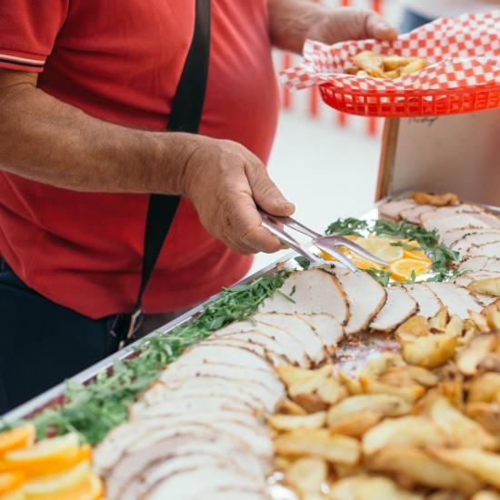 Persona serve cibo da un buffet con patate e carne.