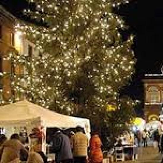 Mercatino di Natale con luci e bancarelle in una piazza storica.