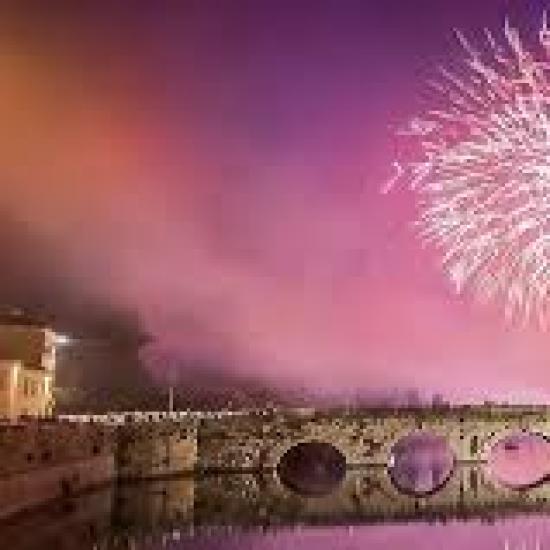 Fuochi d'artificio sopra un ponte storico illuminato di notte.