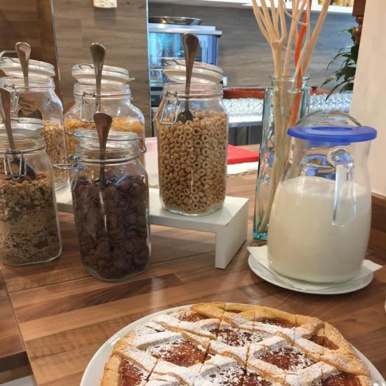 Colazione con crostata e cereali in barattoli di vetro.