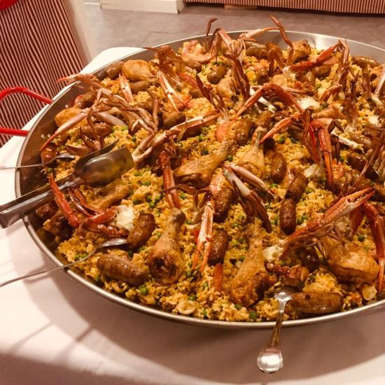 Grande paella con pollo, salsicce e crostacei.