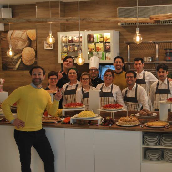 Gruppo di pasticceri felici con dolci in esposizione.