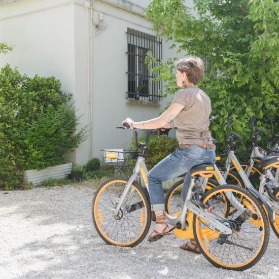 Persona su bici condivisa vicino a una fila di biciclette.