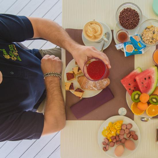 Colazione con frutta, salumi, formaggi e bevande in un ambiente accogliente.