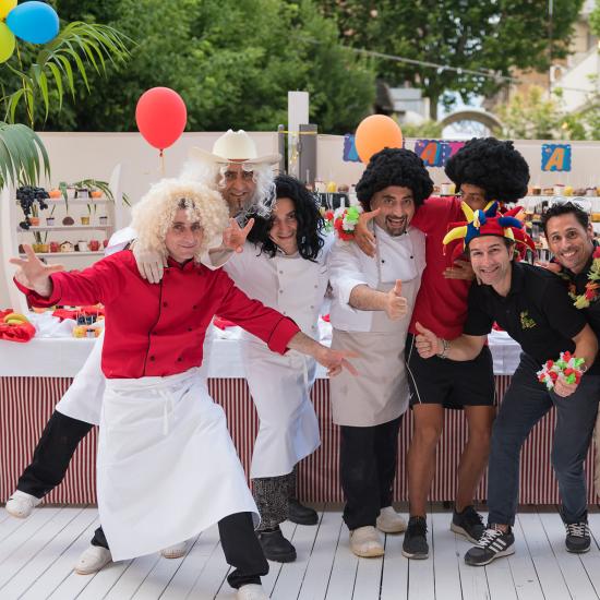 Gruppo di persone in festa con parrucche colorate e abiti divertenti.