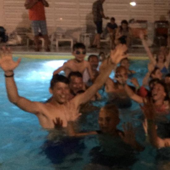 Gruppo di persone in piscina che salutano con entusiasmo.