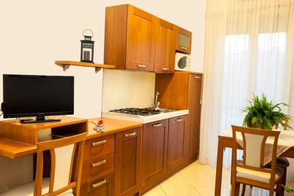 Modern kitchen with wooden cabinets, table, and plant.