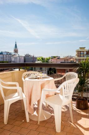 Sunny terrace with table, chairs, and city view.