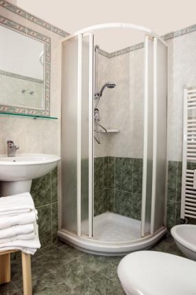 Bathroom with corner shower, sink, and white towels.