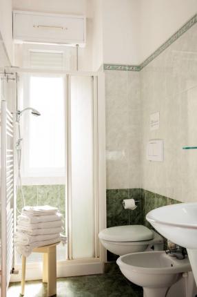 Bright bathroom with shower, sink, and white towels.