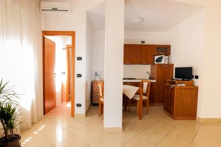 Small kitchen with wooden furniture and table, TV, and plant.