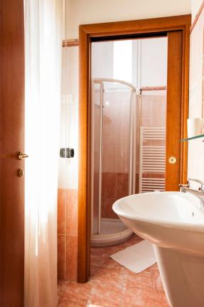 Bathroom with shower, sink, and orange tiles.