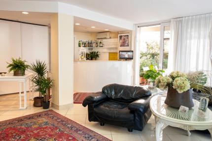 Elegant living room with black sofa, plants, and a bar corner.